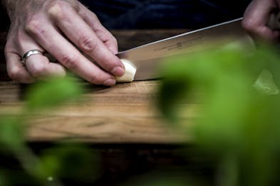 Knoblauch wird auf einem Holzbrett geschnitten