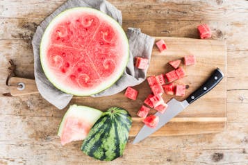 Wassermelone wird auf einem Holzbrett in Stücke geschnitten