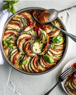 Ratatouille-Auflauf aus runden Tomaten-, Auberginen- und Zucchini Scheiben im Kreis angeordnet in einer Springform