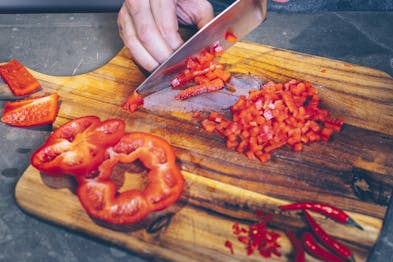 Paprika werden auf Holzbrett für Pesto alla calabrese geschnitten